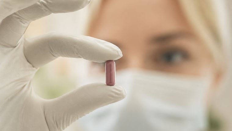 Profissional de saúde segurando uma cápsula de medicamento